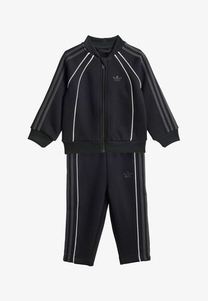 Ensemble de survêtement Adidas noir pour enfants avec veste zippée et pantalon, ornés de liserés blancs et des trois bandes emblématiques sur les manches et les jambes.