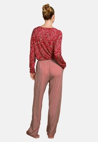 Rode bloemenlange mouwen top gecombineerd met lichtbruine, gestreepte, wijde broek. De stof lijkt zacht; ontspannen fit met een elastische tailleband.