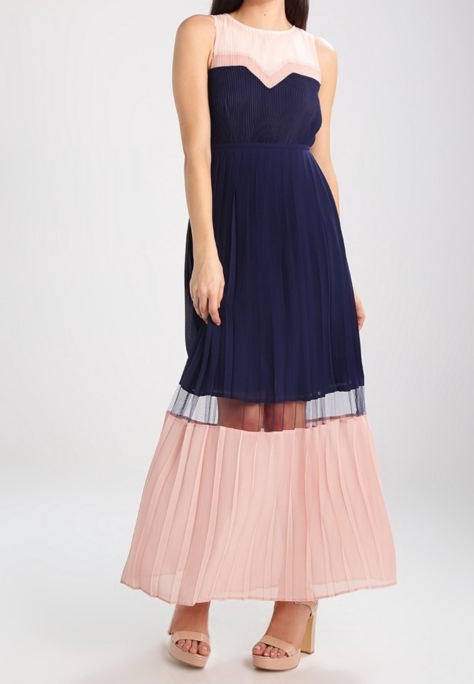 Robe maxi sans manches avec tissu plissé bleu marine, partie supérieure rose clair en motif chevron, et bas fluide à plusieurs couches.