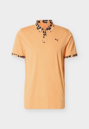 Polo pour homme couleur pêche avec col et bords de manches à motif floral noir, arborant un petit logo Puma sur le côté gauche de la poitrine.