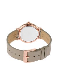 Różowe złote zegarek z okrągłą kopertą, przezroczystym tyłem i jasnoszarym skórzanym paskiem z metalową klamrą oraz wieloma otworami do regulacji.