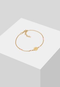 Bracciale in oro con charm rotondo, perline rosa e chiusura regolabile. Il design presenta un motivo delicato e strutturato.
