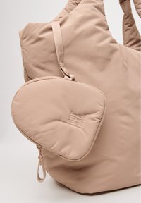 Borsa imbottita rosa chiaro con tasca rotonda rimovibile. Dotata di spallacci regolabili e logo in rilievo, mette in risalto una texture liscia e un design minimale.