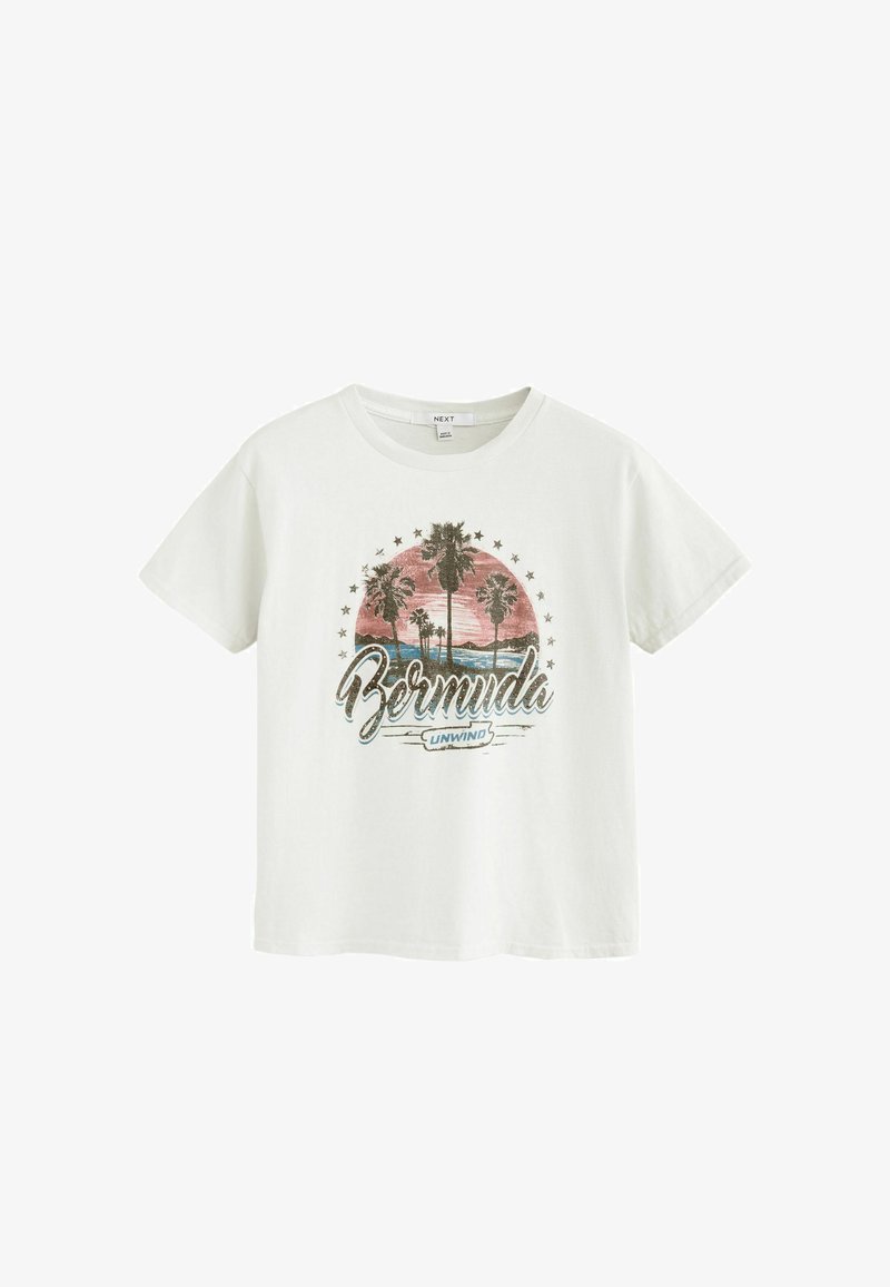 T-shirt blanc avec un coucher de soleil, des palmiers, des étoiles et le texte "Bermuda Unwind" imprimé sur le devant.