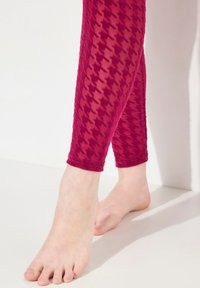 Leggings a scacchi bordeaux con un motivo testurizzato e una vita elastica, accorciati fino al polpaccio, indossati a piede nudo su uno sfondo neutro.