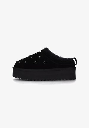 Scarpe slip-on in camoscio nero con foderato in pelliccia sintetica, caratterizzate da dettagli in strass e suola spessa e scanalata. Design snello e arrotondato.