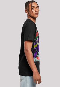 Black cotton t-shirt featuring a graphic print of the Joker in purple and green, with "BATMAN" text in red, displayed on the front.