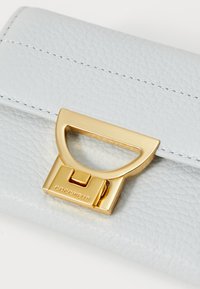 Portefeuille en cuir bleu clair avec une finition texturée, un fermoir en hardware doré accentué et des détails de couture blanche.