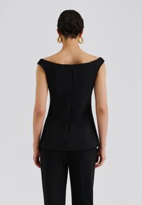 Čierny štruktúrovaný top s výstrihom mimo ramien a zapínaním na zips na chrbte. Hladká textúra s priliehavým strihom a výraznými švami.