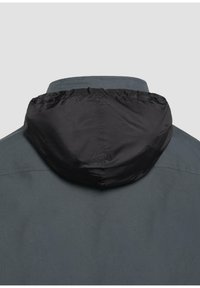 Graue Jacke mit einer schwarzen, verstellbaren Kapuze. Das strukturierte Material zeigt eine glatte Oberfläche, mit sichtbaren Nähten und Details am Halsausschnitt.