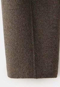 Tissu en laine marron avec une couture verticale au centre, montrant la texture et les détails des fibres.