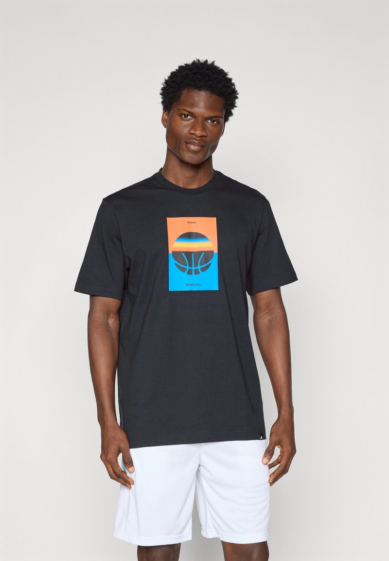 T-shirt en coton noir avec un graphique de basket-ball central en orange et bleu. Manches courtes, col rond et coupe régulière.
