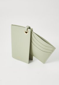 Portafoglio in pelle texturizzata verde chiaro con anello dorato, dotato di più scomparti per carte e un design piegato per un facile accesso.