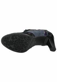Scarpa con tacco in pelle nera e camoscio, con rete decorativa e suola in gomma con motivo floreale. Il tacco è moderatamente elevato.