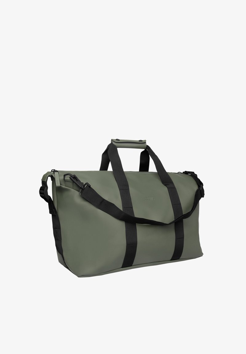 Bolsa de lona verde con correas negras, asas cortas con cierre de presión y correa ajustable para el hombro sobre un fondo blanco.