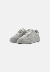 Sneakers in suede grigio con una finitura testurizzata, punta tonda e suola in gomma piatta. Presentano lacci abbinati e un design minimalista per un aspetto elegante.