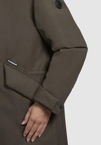 Brun, tekstureret overtøj med opsmøgte ærmer. Har et sort logo-patch og en sidelomme. Skræddersyet pasform med knapdetaljer.