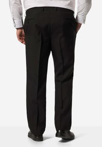 Pantaloni neri in tessuto liscio, caratterizzati da una vestibilità sartoriale, piega frontale e tasche standard con dettagli di cucitura discreti.