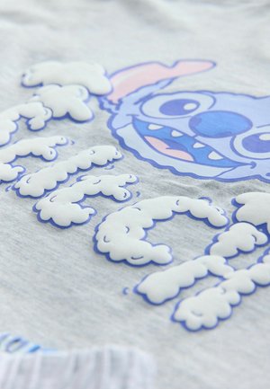 Graues T-Shirt mit einem blauen, cartoonhaften Charakter mit großen Augen und breitem Mund, umgeben von weißen, wolkenartigen Textelementen.