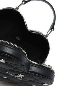 Černá prošívaná kabelka se zipem v stříbrném odstínu, ve tvaru srdce, hladkým koženým povrchem a odnímatelným popruhem. Vnitřní část není podšitá.