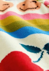 Knit fabric featuring a pattern of smiling faces, wavy stripes in colors blue, yellow, pink, green, with accents of red and teal leaves.