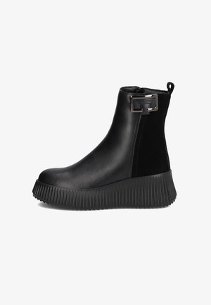 Czarne botki za kostkę z gładkiej skóry, z teksturowaną gumową podeszwą o żebrowanym wzorze oraz dekoracyjnym akcentem w postaci klamry z boku.