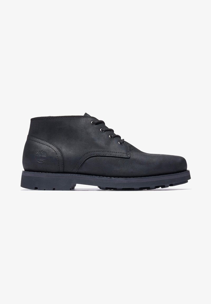 Bottine montante en cuir noir à lacets avec semelle épaisse en caoutchouc et logo embossé sur le talon, présentée de profil sur fond blanc.