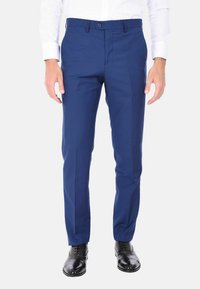 Pantaloni blu navy con vestibilità su misura, caratterizzati da un frontale piatto, passanti per cintura e chiusura con un solo bottone, abbinati a scarpe eleganti nere lucide.