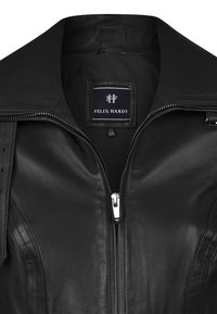 Giubbotto in pelle nera con chiusura a zip, colletto a punta e etichetta interna che recita "Felix Hardy." Texture liscia e design tailored.