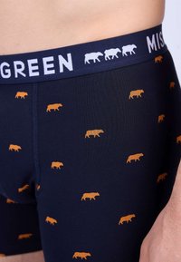 Boxers pour hommes en jersey de coton marine, avec un imprimé animal orange et une ceinture blanche contrastante portant le mot "GREEN."