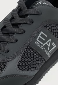 Basket noire Emporio Armani EA7 avec panneaux en mesh, lacets et logo visible de la marque sur le côté.