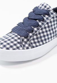 Granatowo-białe tenisówki z płótna w kratkę gingham, z okrągłymi sznurowadłami, białą gumową podeszwą i teksturowanym bocznym panelem. Posiadają metalowe przelotki.
