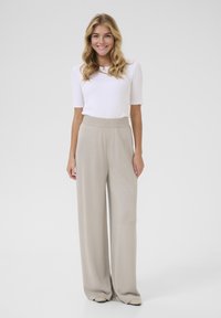 Light beige wide-leg pants with a soft texture and subtle shimmer, paired with a fitted white short-sleeve top.