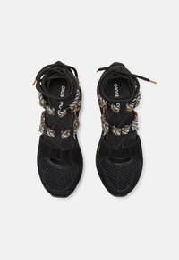Baskets de sport noires avec un devant en maille, des sections en suède texturé et des lacets à motifs aux couleurs noire, blanche et orange.
