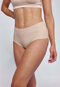 Mutande hipster beige senza cuciture con una texture liscia e una fascia larga e morbida. Progettate per una vestibilità comoda e una minima visibilità sotto i vestiti.