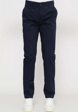 Pantaloni di cotone blu navy con una vestibilità dritta, dotati di tasche frontali e chiusura con bottone, abbinati a sneakers bianche.