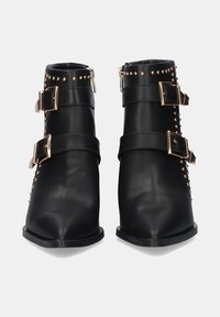 Botines negros de cuero con punta afilada, que cuentan con hebillas en tono dorado y acentos de tachuelas a lo largo de los laterales.