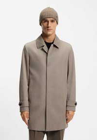 Beige uldblandingsfrakke med en struktureret design, spids krave og knapmanchetter. En ribbet beige hue fuldender looket.