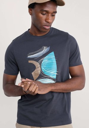 Tricou scurt cu mânecă, de un albastru închis, cu modele abstracte în nuanțe de albastru deschis, maro și alb. Material din bumbac neted cu guler rotund.