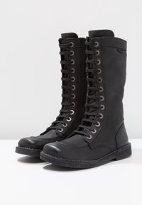 Bottes montantes noires à lacets en simili cuir lisse, avec des semelles en caoutchouc, des œillets en métal et une fermeture éclair sur le côté pour un enfilage facile.