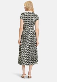 Sukienka o długości średniej z krótkimi rękawami, z geometrycznym wzorem w kolorach granatowym, kremowym i oliwkowym. Zwiewny materiał z dopasowaną talią.