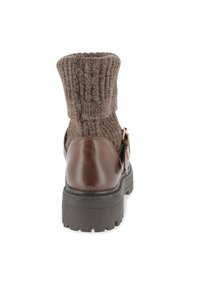 Stivale alla caviglia in pelle marrone con parte superiore in maglia marrone a coste, suola piatta in gomma e una fibbia decorativa sul lato.