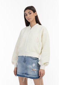 Witte textuur bomberjack met een ritsluiting en een voorklep, gecombineerd met een versleten denim minirok. Casual, losse pasvorm.
