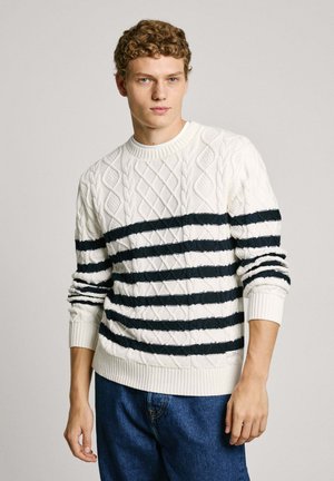 Chunky knit sweater in cream with navy horizontal stripes. Features textured diamond pattern, ribbed cuffs and hem, and relaxed fit.