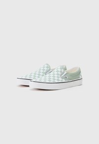 Green and white slip-on sneakers with a checkerboard pattern, rubber sole, and subtle black accents along the edge.