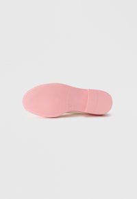Pink rubber shoe sole with a textured surface, featuring a rounded shape and moderate heel elevation. No logos or patterns visible.