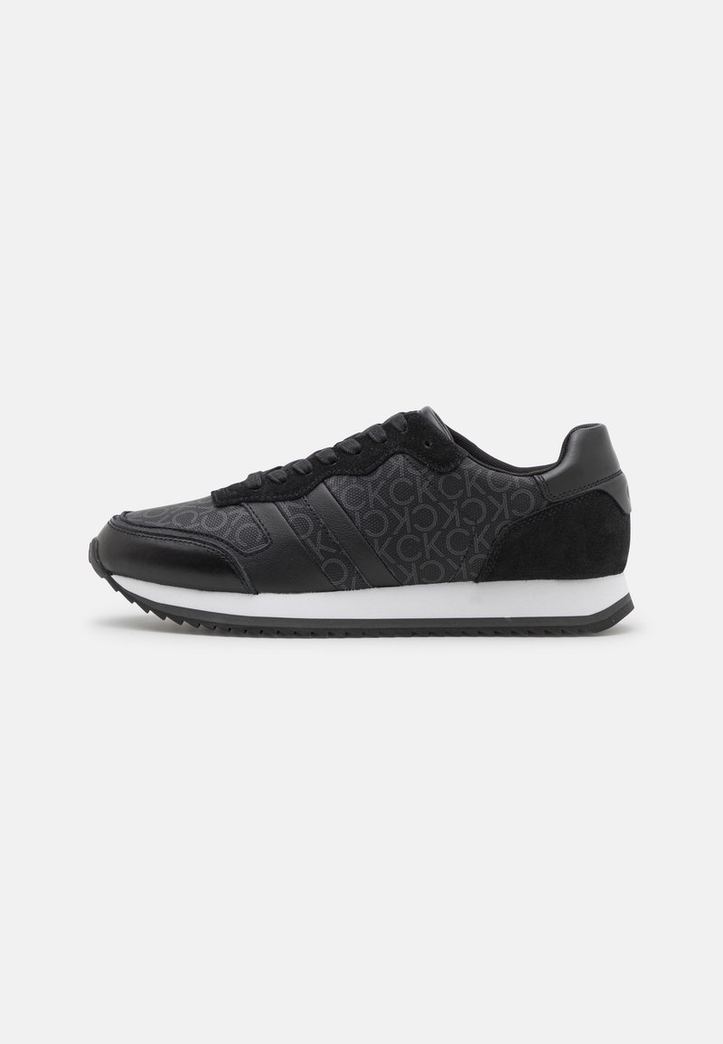 Black athletic sneakers featuring a textured fabric upper, smooth leather accents, a white midsole, and black rubber outsole with grip.