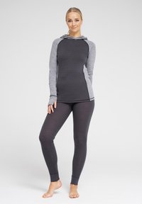 Grå og sort atletisk tøj bestående af en langærmet hættebluse med raglanærmer og tætsiddende leggins, lavet af et glat, tekstureret stof.