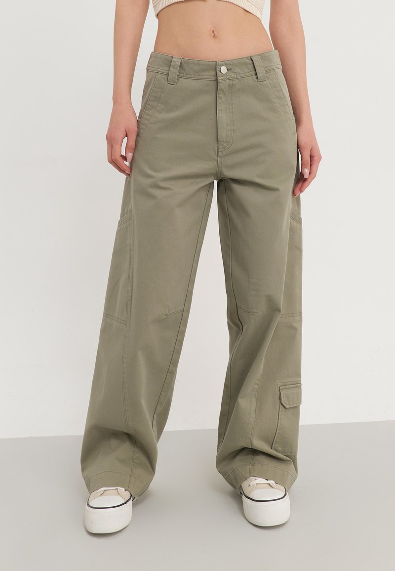 Pantalons cargo à larges jambes en vert olive, avec une taille haute, des poches avant et des poches à soufflet sur les côtés. Fabriqués en tissu coton robuste.