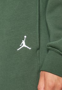 Groene sweatshirt met een zachte textuur, voorzien van een witte Jumpman-logo op de borst. Gedetailleerde stiksels langs de naden en manchetten.
